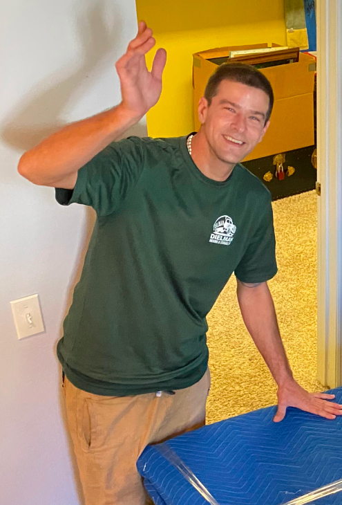 A Dielman Moving crew member in a green branded shirt at a customer's home